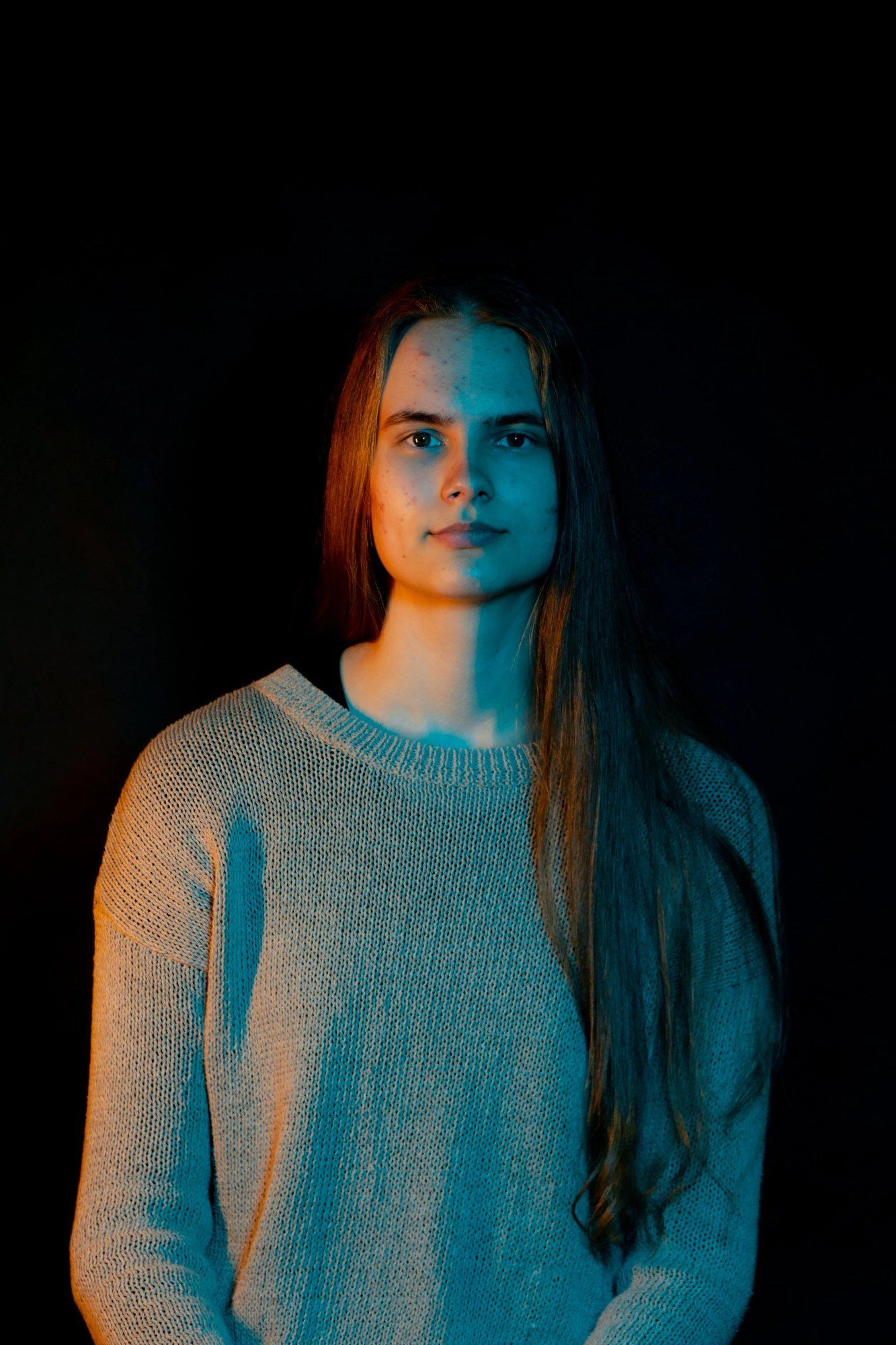 Muotokuva pitkähiuksisesta naisesta tummaa taustaa vasten